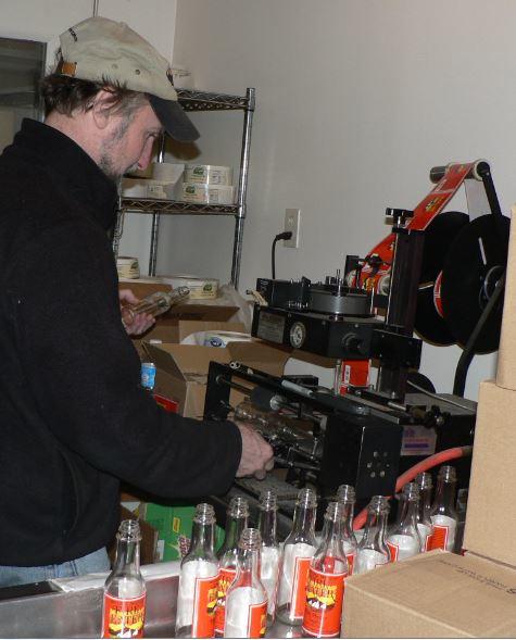 Dennis Proctor of Mother's Mountain in Falmouth labels jars for the company's popular Fire Eater hot pepper sauce.